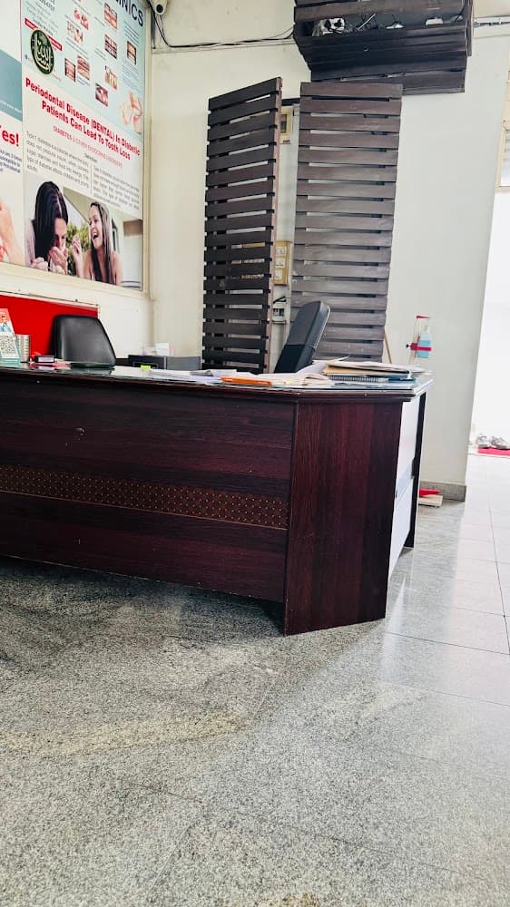 Dr Bhat's consultation desk: a dark wooden desk with files, in front of slatted wooden panels